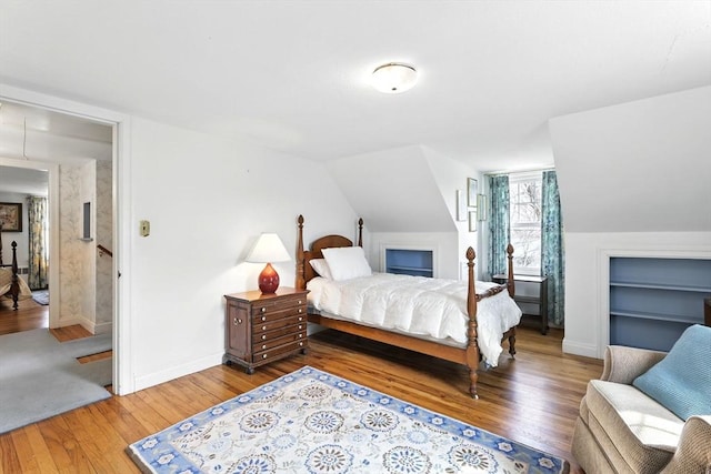 bedroom featuring baseboards, vaulted ceiling, and hardwood / wood-style flooring