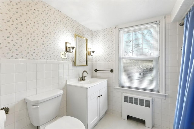 bathroom featuring radiator, wainscoting, toilet, tile walls, and wallpapered walls