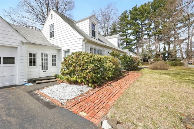 view of property exterior with a lawn and a shingled roof