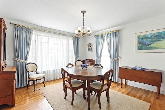 dining room featuring baseboards, an inviting chandelier, and light wood-style floors