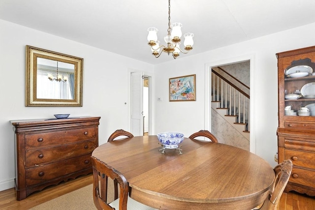 dining room featuring an inviting chandelier, light wood-style floors, and stairs