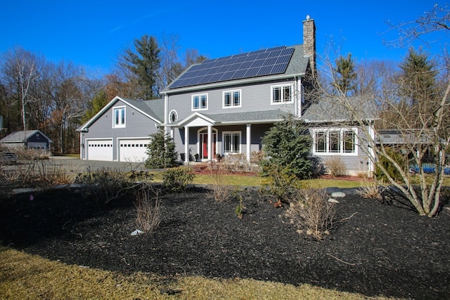 view of front of property featuring solar panels, covered porch, and a garage