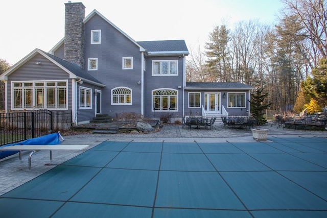 rear view of house featuring a covered pool and a patio