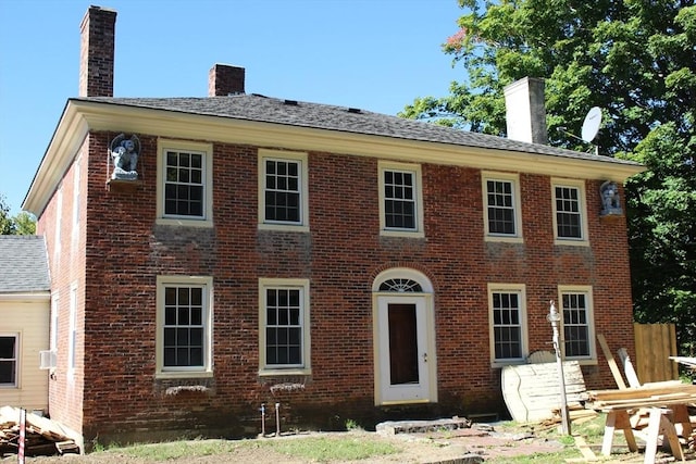colonial inspired home featuring brick siding and a chimney