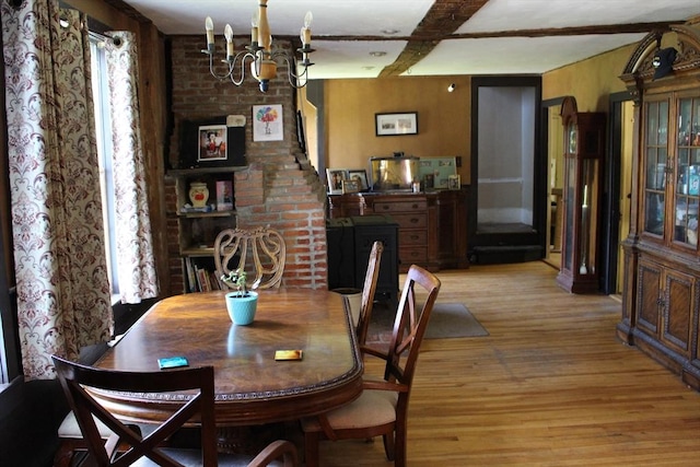 dining area with a chandelier, light wood-type flooring, and beamed ceiling