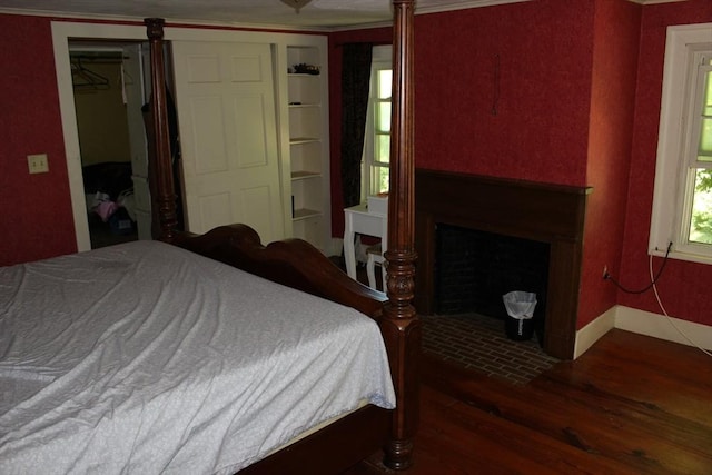 bedroom with a fireplace with flush hearth, baseboards, and wood finished floors