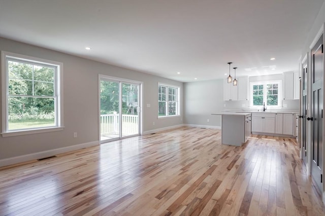 72 N Mast St Unit 1, Goffstown, NH 03045 - kitchen with light wood finished floors, open floor plan, white cabinets, light countertops, and a kitchen island