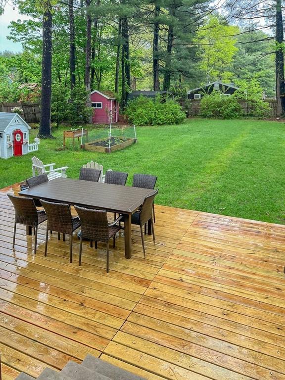 wooden terrace featuring a storage shed and a lawn