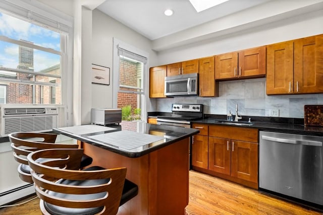 390 Riverway Unit 24, Boston, MA 02115 - kitchen with stainless steel appliances, a baseboard radiator, a sink, a kitchen bar, and brown cabinetry