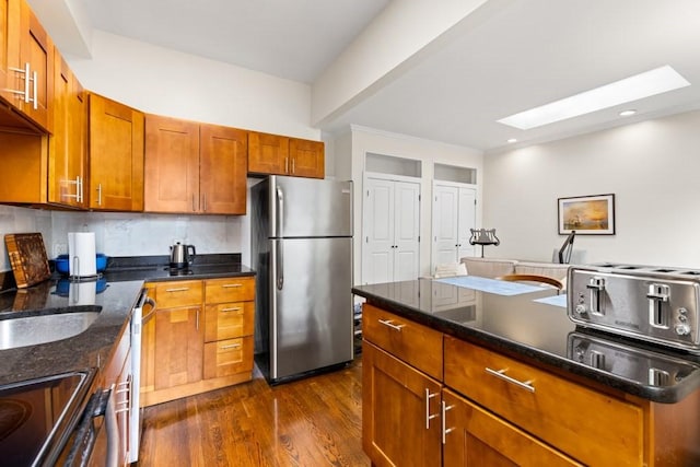 390 Riverway Unit 24, Boston, MA 02115 - kitchen featuring appliances with stainless steel finishes, a skylight, dark wood-type flooring, brown cabinetry, and recessed lighting