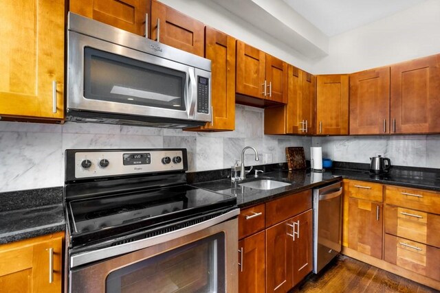 390 Riverway Unit 24, Boston, MA 02115 - kitchen featuring stainless steel appliances, a sink, backsplash, dark stone counters, and dark wood-style flooring