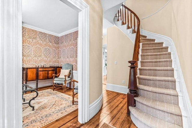 stairs with hardwood / wood-style floors and ornamental molding