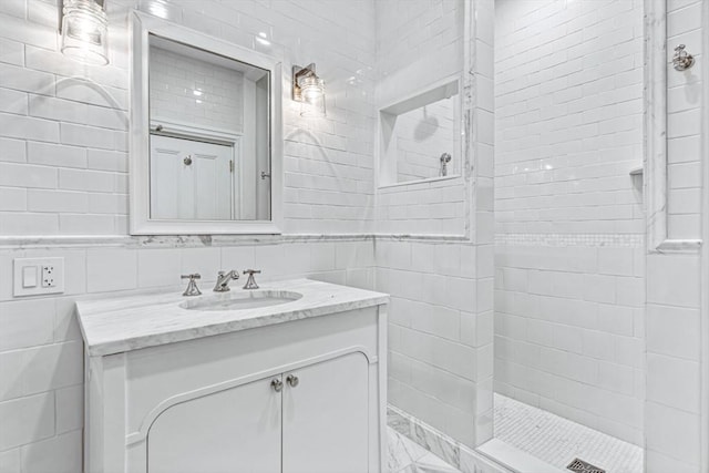 bathroom featuring a tile shower, vanity, and tile walls