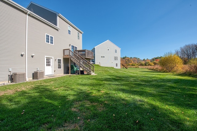 rear view of property featuring central air condition unit, a wooden deck, and a yard