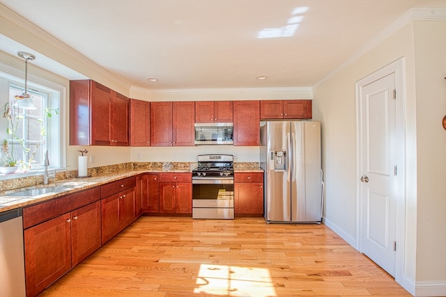 kitchen with appliances with stainless steel finishes, ornamental molding, decorative light fixtures, and light wood-type flooring