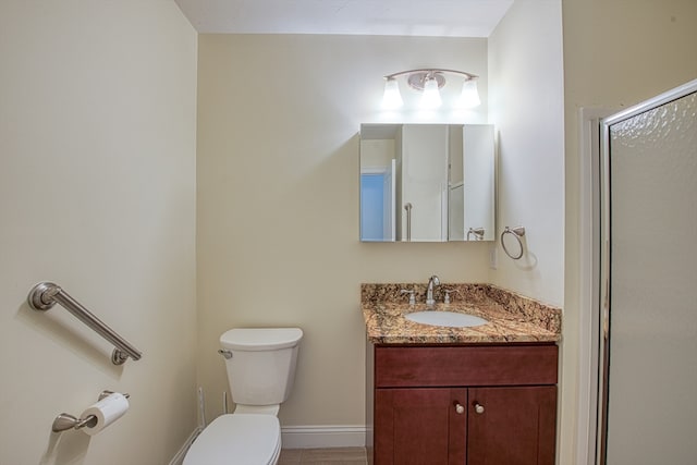 bathroom featuring vanity, a shower with shower door, and toilet