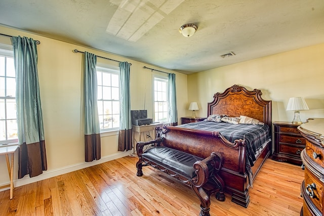 bedroom featuring light hardwood / wood-style floors and a textured ceiling