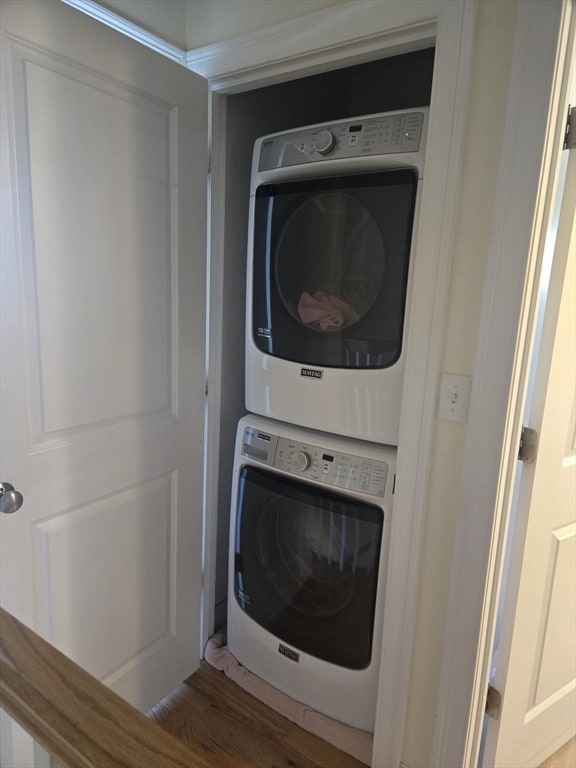 clothes washing area featuring stacked washing maching and dryer and hardwood / wood-style flooring