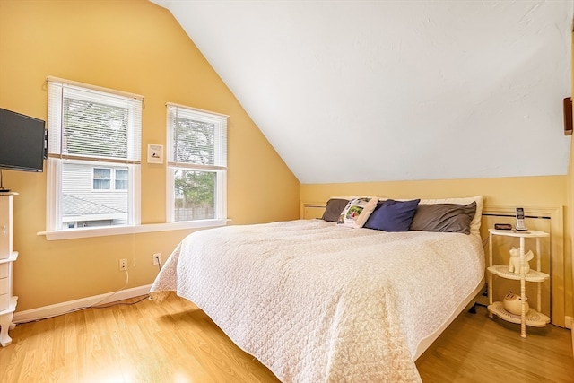 bedroom featuring light wood-type flooring and vaulted ceiling