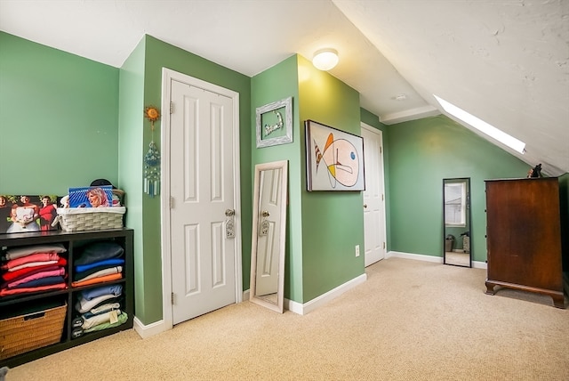 bonus room featuring vaulted ceiling with skylight and light carpet