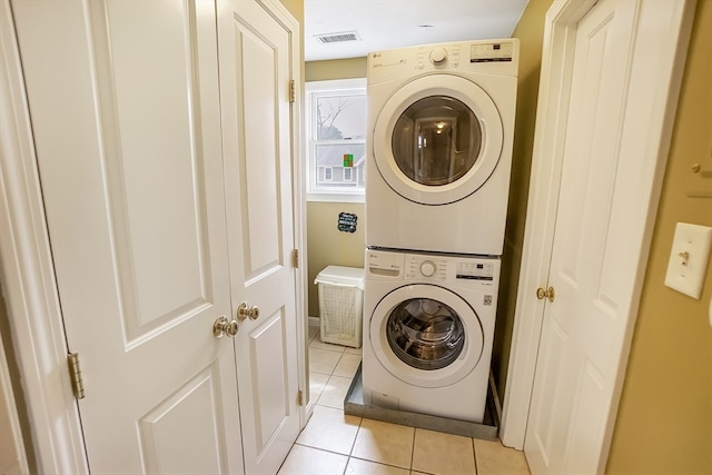 laundry room featuring light tile patterned floors and stacked washer / dryer