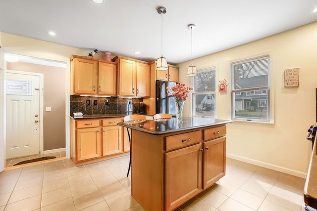 kitchen featuring a kitchen island, pendant lighting, light tile patterned floors, stainless steel refrigerator, and decorative backsplash