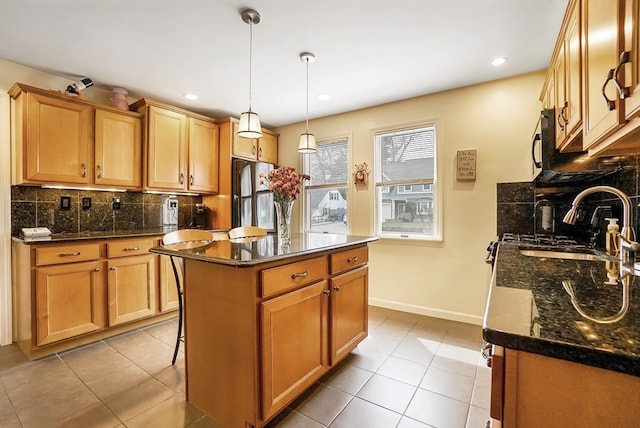 kitchen with a kitchen island, tasteful backsplash, hanging light fixtures, stainless steel refrigerator, and dark stone countertops