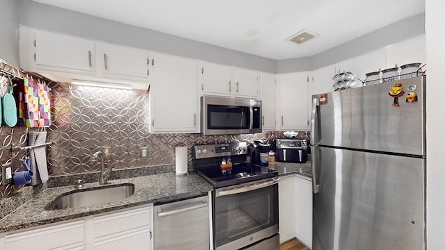 kitchen featuring dark stone countertops, visible vents, appliances with stainless steel finishes, and a sink