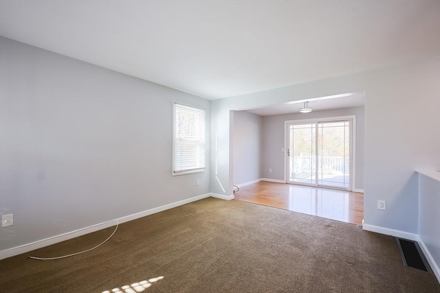 carpeted spare room with visible vents and baseboards