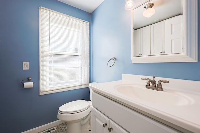 half bathroom featuring vanity, toilet, and baseboards