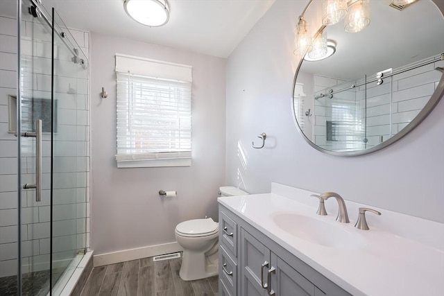 bathroom featuring toilet, wood finished floors, vanity, baseboards, and a shower stall