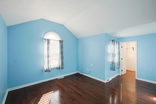 additional living space with baseboards, visible vents, vaulted ceiling, and hardwood / wood-style floors