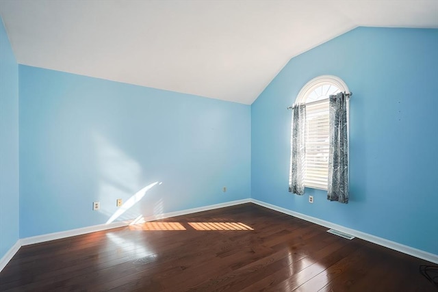 additional living space with dark wood-style floors, baseboards, visible vents, and vaulted ceiling