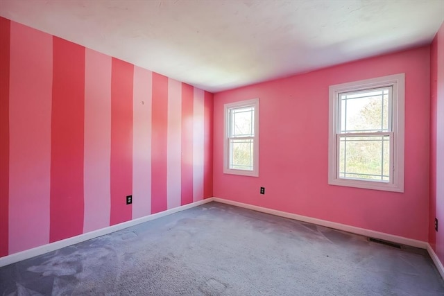 empty room featuring wallpapered walls, carpet floors, visible vents, and baseboards