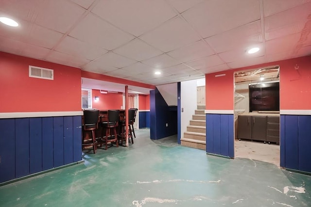 interior space with a wainscoted wall, stairway, visible vents, and concrete flooring