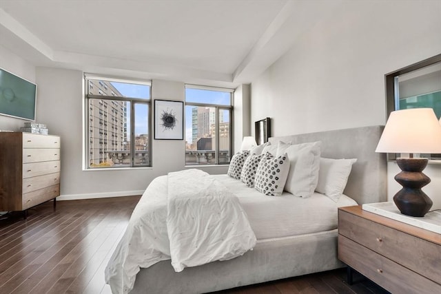bedroom with wood-type flooring, a raised ceiling, and baseboards