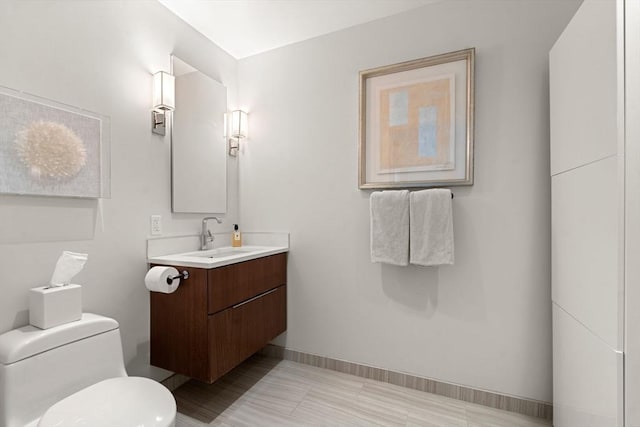 bathroom featuring vanity, baseboards, and toilet