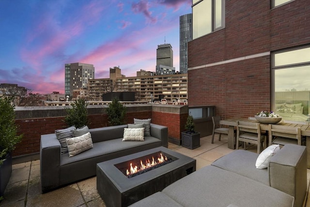 patio terrace at dusk featuring an outdoor living space with a fire pit and a city view