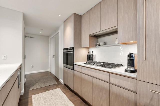 kitchen featuring light countertops, stainless steel appliances, light brown cabinetry, and tasteful backsplash
