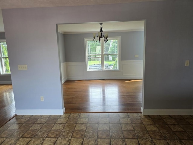 62 Saint Anthony St, Fitchburg, MA 01420 - unfurnished dining area featuring a chandelier, healthy amount of natural light, dark stone finish floors, a wainscoted wall, and crown molding
