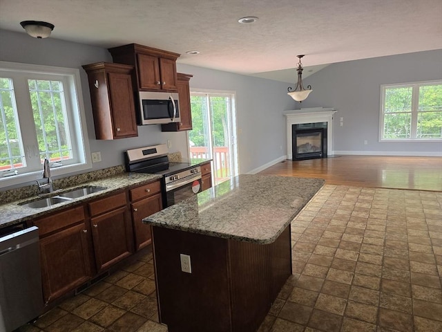62 Saint Anthony St, Fitchburg, MA 01420 - kitchen featuring stainless steel appliances, open floor plan, a glass covered fireplace, stone countertops, and decorative light fixtures