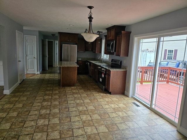 62 Saint Anthony St, Fitchburg, MA 01420 - kitchen featuring stainless steel appliances, decorative light fixtures, a center island, light stone counters, and dark brown cabinetry