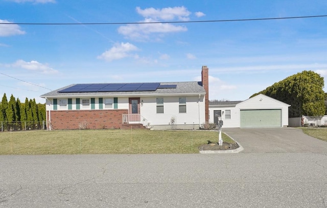 ranch-style house featuring an outbuilding, a front lawn, fence, solar panels, and a chimney