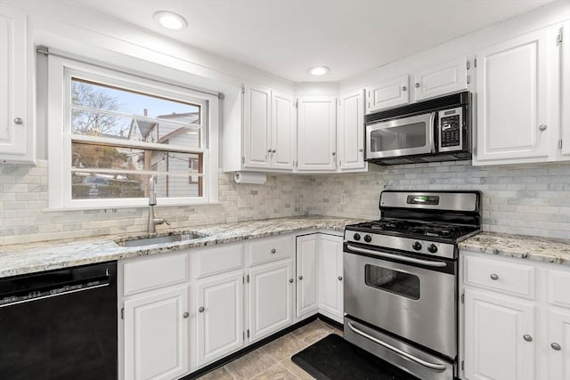 kitchen with appliances with stainless steel finishes, a sink, white cabinetry, and tasteful backsplash