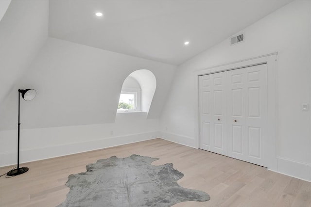 unfurnished bedroom with a closet, light hardwood / wood-style flooring, and vaulted ceiling