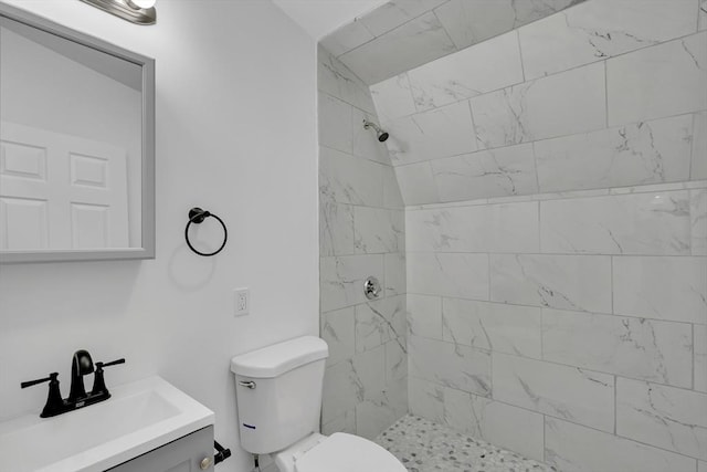 bathroom featuring a tile shower, vanity, and toilet