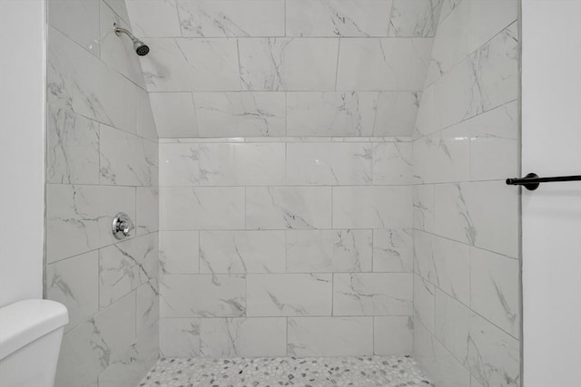 bathroom featuring toilet and a tile shower