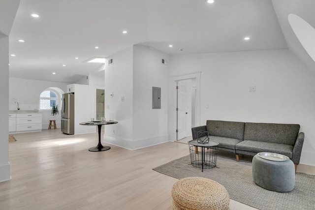 living room featuring electric panel, light hardwood / wood-style floors, and lofted ceiling