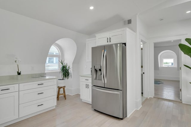 kitchen with white cabinets, stainless steel fridge with ice dispenser, light hardwood / wood-style flooring, and lofted ceiling