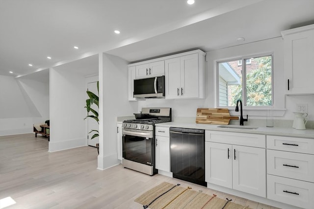 kitchen with sink, white cabinets, light hardwood / wood-style floors, and appliances with stainless steel finishes